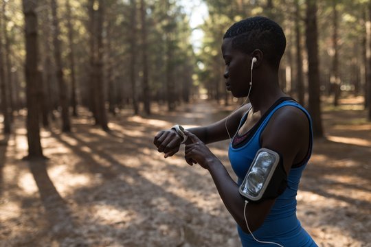 Female athlete looking at smartwatch while exercising outdoors