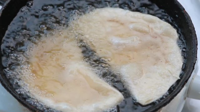 Close-up, frying chebureks in hot oil. Cheburek fried pie with meat.