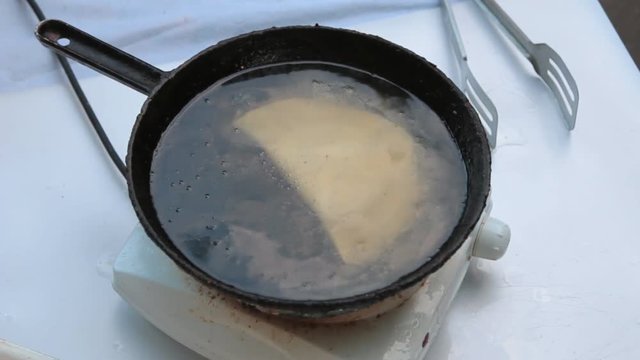 Put the raw chebureks in a frying pan with hot oil. Cheburek fried pie with meat.