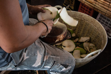 man worker chopped a coconut with basket in market