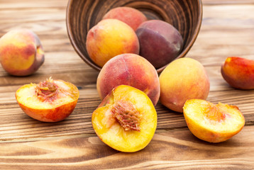 Fototapeta na wymiar Whole peaches and halves of peaches with bowl on wooden table.