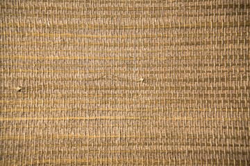 Closeup of a trendy straw wallpaper of ethnic style. Woven pattern background with bamboo and grass.