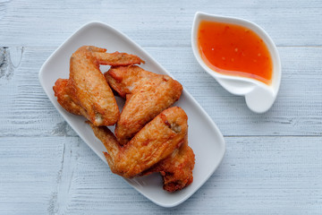 Top view and close up: Deep Fried Chicken wing in white plate with sweet sauce on wooden background. Popular food for kids.