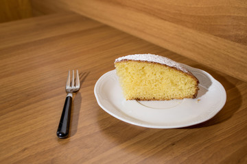 Slice of a delicious cake with powdered sugar on a white plate
