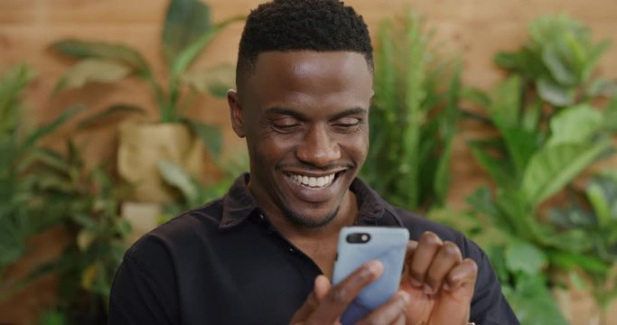 portrait of african american man using smartphone browsing online messages smiling enjoying texting mobile communication slow motion 