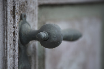 Old rusty front door handle close-up on a wooden door with cracked paint.