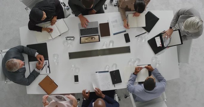 senior business executives in boardroom meeting sharing wind turbine project development with clients using tablet pc technology corporate leadership team overhead