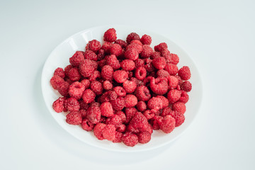 Raspberry berries on a plate on a light background