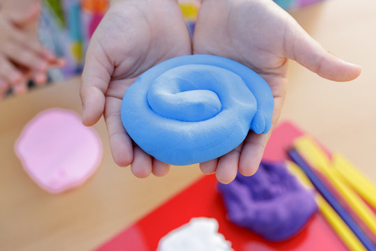 Hands Holding a Lump of Blue Modeling Clay