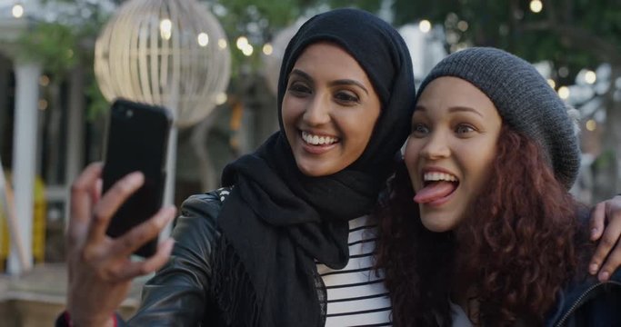 portrait young diverse women friends using smartphone taking selfie photo making faces enjoying relaxed fun girlfriends hang out in city slow motion