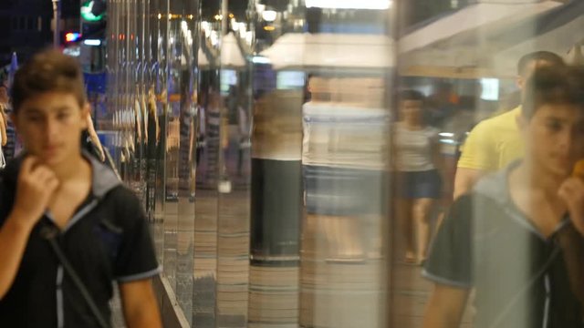 People in reflection of building in the evening. Timelapse of crowd.
