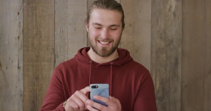 portrait of young man using smartphone texting browsing online enjoying sending sms messages mobile communication smiling happy slow motion