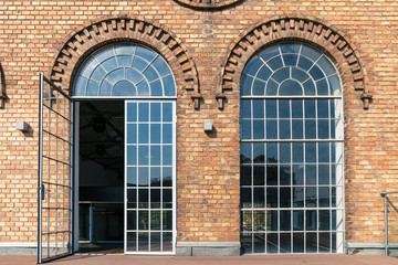 Fototapeta na wymiar Backsteinfassade eines alten Fabriksgebäude mit großflächigen Fenstern und schönen Verzierungen