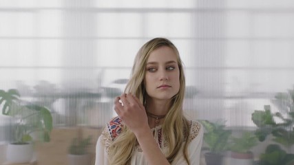 portrait of beautiful young blonde woman intern looking at camera running hand through hair in office workspace background
