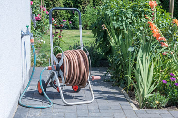 Aufgerollter Gartenschlauch an einer Kaltwasserleitung