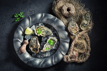 Top view of oysters with lemons on dark plate