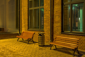 Obraz na płótnie Canvas Evening in the old quarter. Office building in loft style. Brick building with large Windows, two benches and an urn.