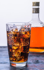 a glass of ice and a bottle with a drink