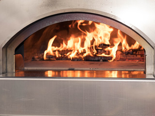 Fototapeta premium The working furnace for preparation of pizza. Inside burns firewood and big fire rises