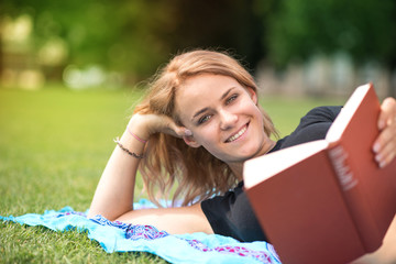 Junge Frau lacht und liest ein Buch