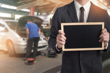 Obraz premium Mechanic hand checking and fixing a broken car in garage.Inspector with tablet are checking list the car in car factory