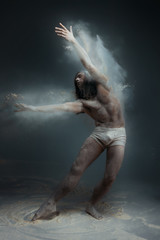 Dancing in flour concept. Muscle fitness guy man male dancer in dust / fog. Guy wearing white...