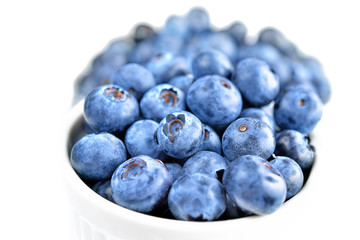 Fresh colorful Bilberries blueberries in white bowl isolated on white background. Selective focus