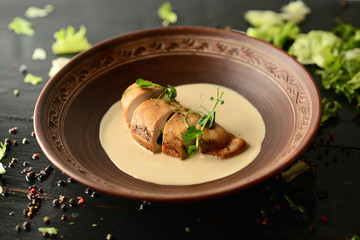 baked chicken fillet with cheese and sauce on a clay plate