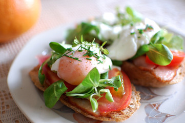 Poached eggs on toast with tomato, bacon and herbs.