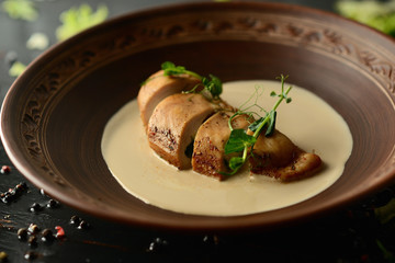 baked chicken fillet with cheese and sauce on a clay plate