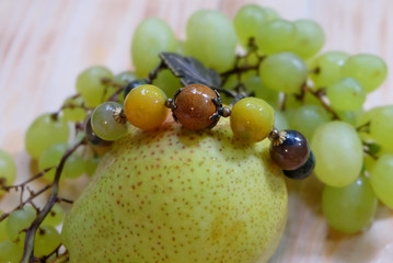 Handmade bracelet made from natural stones, grapes and pear. Composition with jewelry and fruits.