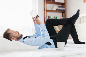 Businessman on bed working with a tablet from his hotel room