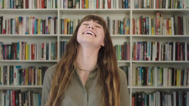 portrait of young happy caucasian woman laughing cheerful cute librarian in library bookshelf background