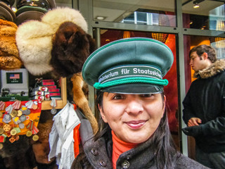 Touristin in Berlin mit Stasi Mütze vor Souvenirladen