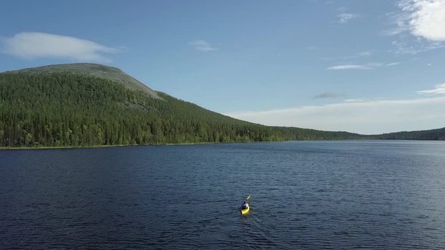 Young male kayaking around in lake Kesankijarvi in Lapland Finland.