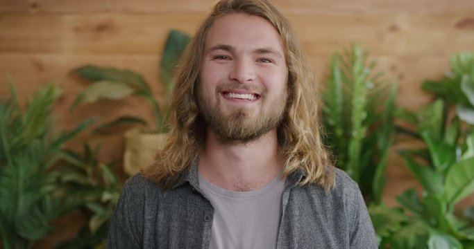 portrait of charming young man smiling happy enjoying successful lifestyle blonde caucasian male with long hair slow motion