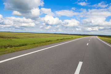 Fototapeta premium Beautiful and sunny road landscape with sky clouds and yellow fields