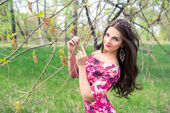 Beautiful girl holding hands branches of trees. Young woman in a forest park