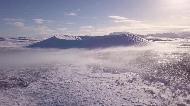 Drone footage from the volcano crater Hverfjall in Iceland during a winter morning with fog. The drone rises out of the fog.