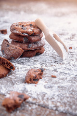 Cookies with chocolate slices sprinkled with powdered sugar and a wooden measuring spoon. Fresh pastry on wooden background.