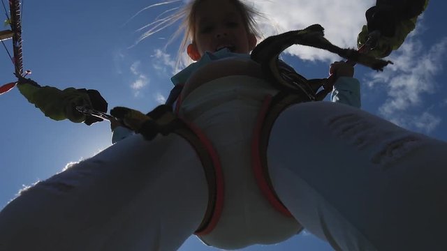 Little girl having fun while bungee jumping up high on trampoline. Little girl bouncing up and down on a bungee trampoline.