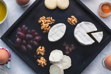 Frühstück Brunch Käse Teller Platte mit verschiedenen Käsesorten, Trauben, Walnüssen und Rosinen serviert in einem Restaurant auf einer schwarzen Holz Platte