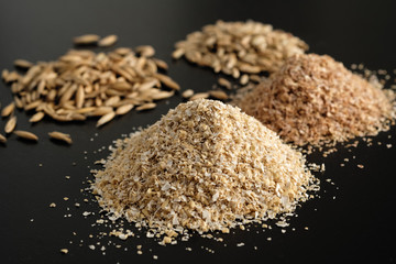 Bran oatmeal with a large grind, with grains of oats and wheat on a black background. Useful, cleansing, for a healthy diet