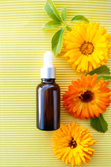 Bottles with flower calendula oil on yellow  backgraund,  flat lay, bio, organic , nature cosmetics concept