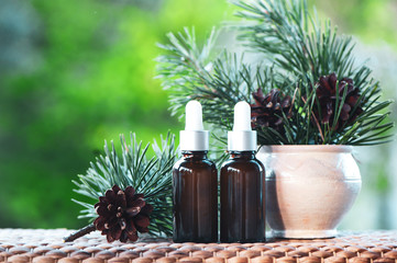 Bottles with pine oil and fresh fir branches  on a natural green background,  bio, organic , nature cosmetics concept