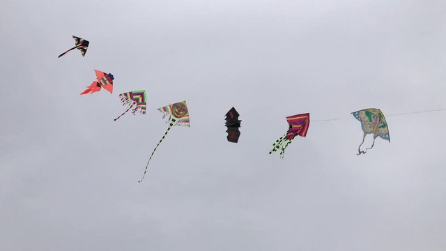 Colorful kites flying on wind in the gray sky with clouds
