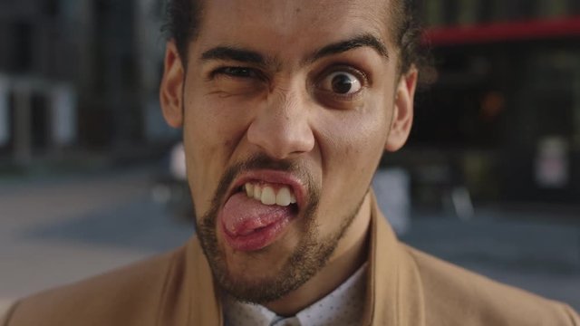 portrait of young attractive mixed race man making faces looking at camera funny crazy