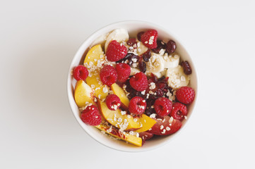 Bowl with nectarine, raspberry, banana, dried cranberry, plum and oats. Fruit salad. Plant based nutrition