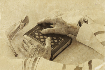 Old Jewish man hands holding a Prayer book, praying, next to tallit and shofar (horn). Jewish...