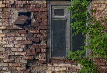 An old window on the background of a brick wall of an abandoned house.